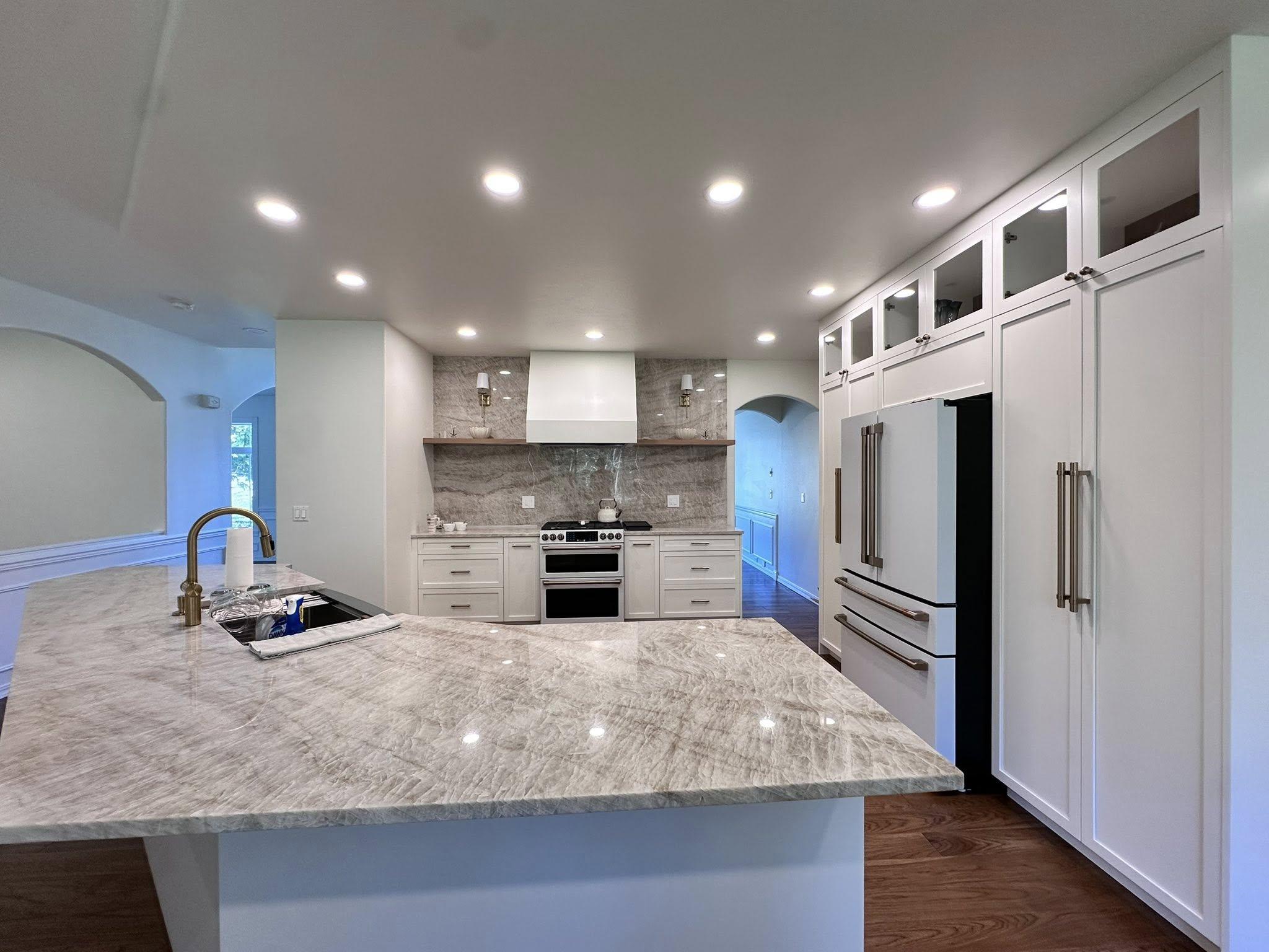 Open concept kitchen remodel with marble countertop island, recessed lighting, and stone backsplash